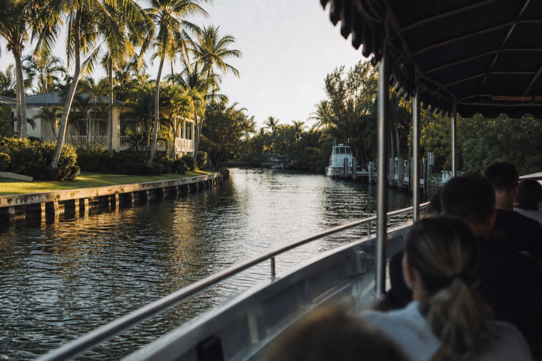 A double-decker cruise boat leaving a downtown marina at golden hour, no text, no logos, no people