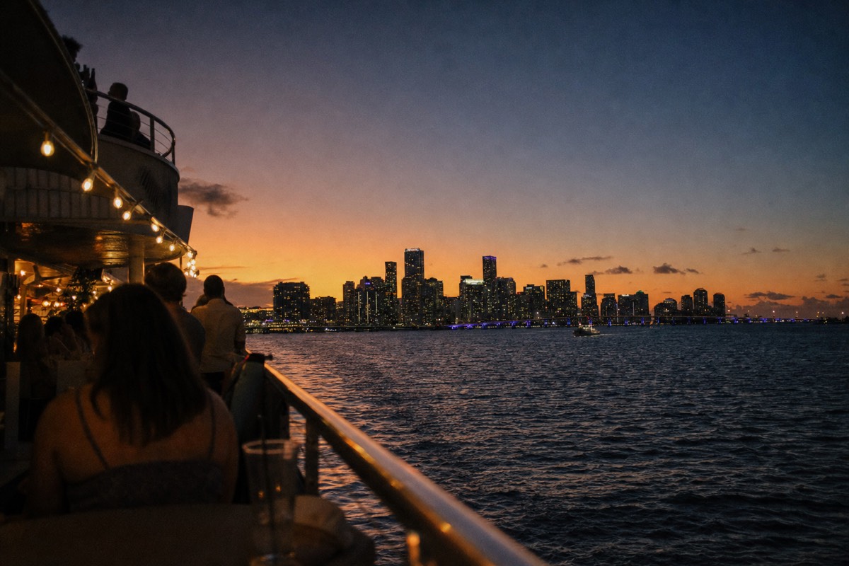 A decorated cruise boat on Biscayne Bay at sunset with the Miami skyline behind it, no text, no logos, no people.