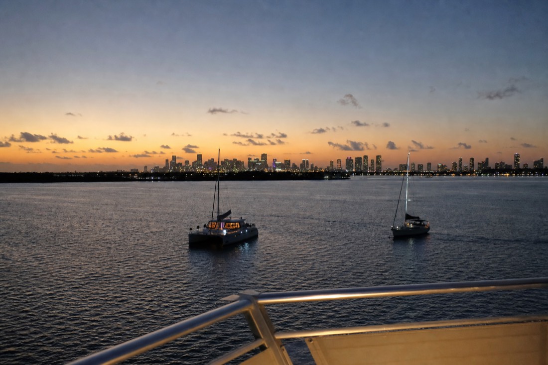 A catamaran and sailboat anchored in calm bay water during golden hour near Miami, no text, no logos, no people