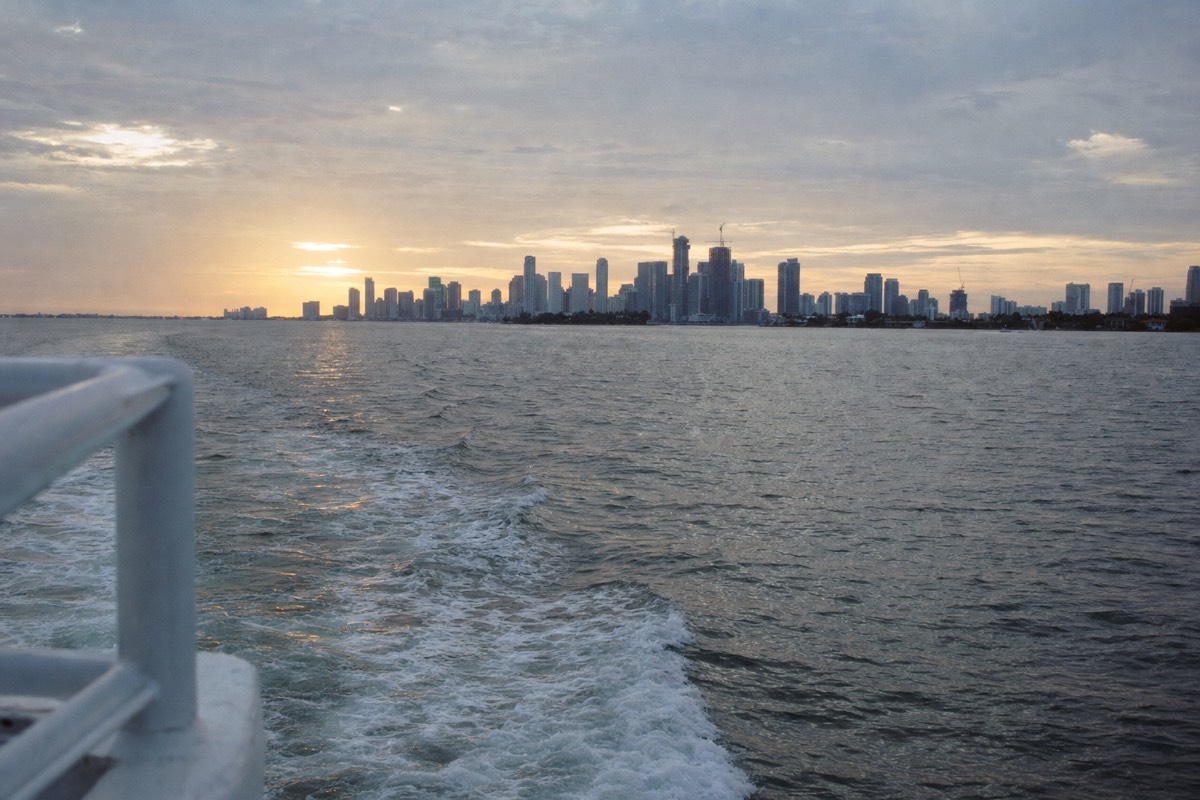 Golden sunset over Biscayne Bay with Miami skyline in background, no text, no logos, no people.