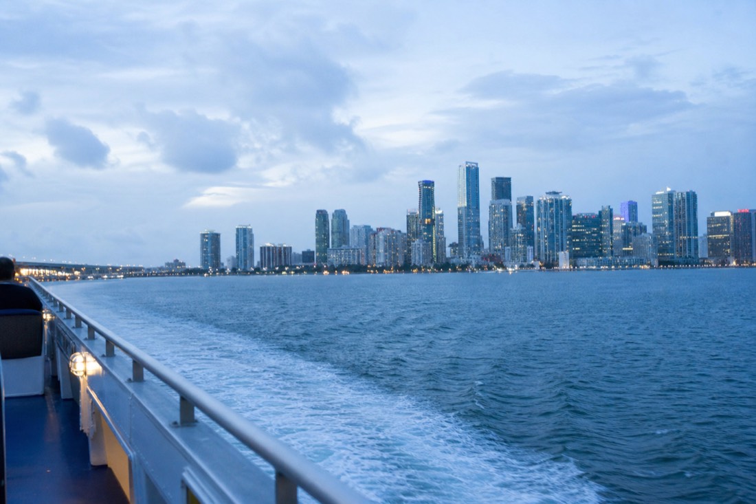 An open-deck passenger boat passing the Miami skyline on a clear afternoon, no text, no logos, no people.