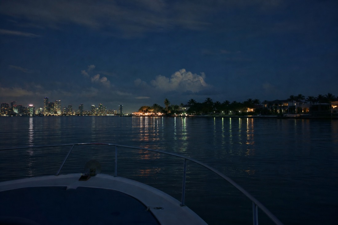 A narrated tour boat passing waterfront mansions on Star Island across calm bay water, no text, no logos, no people.