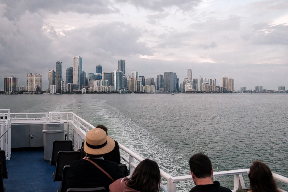 Passengers boarding a sunset cruise boat at a Bayside marina dock in golden light, no text, no logos, no people