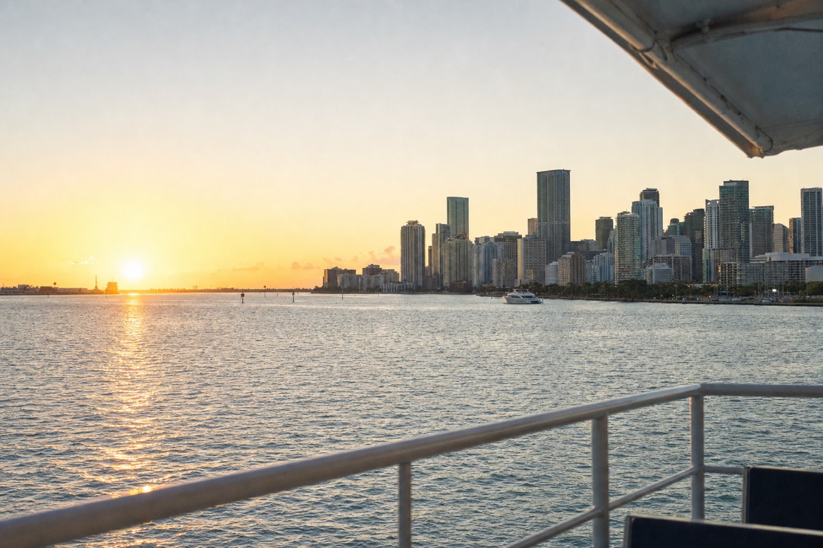 A dinner cruise boat gliding past the illuminated downtown Miami skyline at dusk, no text, no logos, no people.