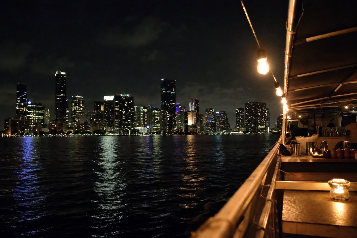 A boat cruising Biscayne Bay at dusk with the Miami skyline glowing behind it, no text, no logos, no people.