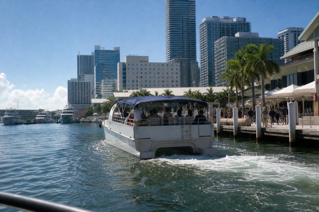 Passengers on a shared sunset cruise watching the Miami Beach skyline light up across the water, no text, no logos, no people.