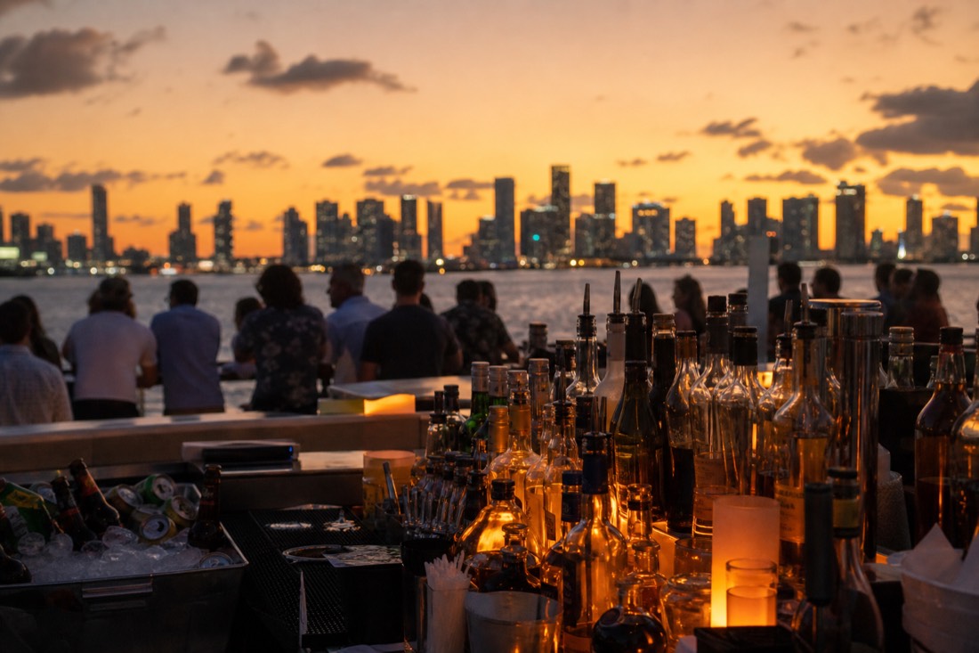 Open-air boat deck at dusk with Miami skyline lights reflecting on Biscayne Bay, no text, no logos, no people