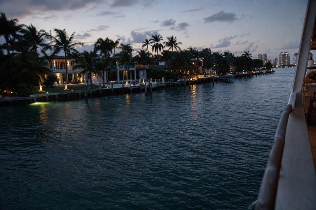 A sightseeing boat cruising past waterfront mansions on Biscayne Bay at sunset, no text, no logos, no people
