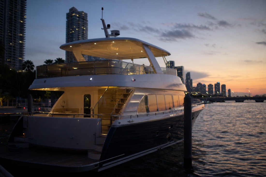 A double-deck sightseeing yacht moored at a downtown Miami marina at dusk, no text, no logos, no people.