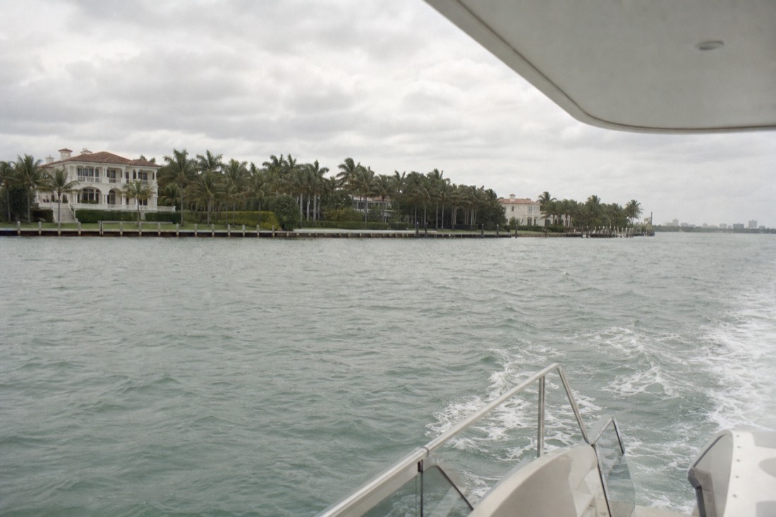 A cruise boat gliding past Star Island mansions along the Biscayne Bay shoreline, no text, no logos, no people