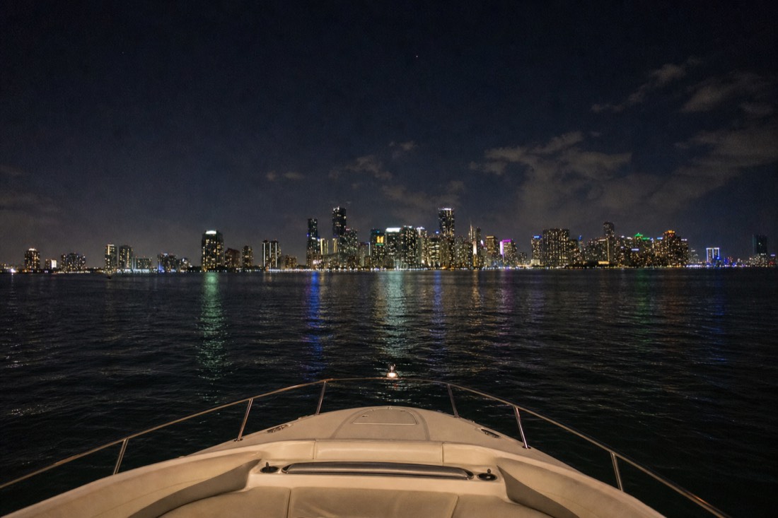 Downtown Miami towers lit up at night as seen across Biscayne Bay from the water, no text, no logos, no people