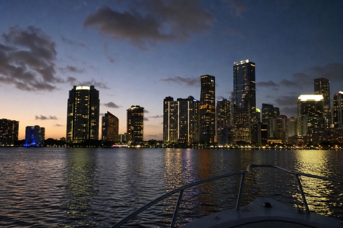 Open-bar sunset cruise passing the downtown Miami skyline on Biscayne Bay at dusk, no text, no logos, no people