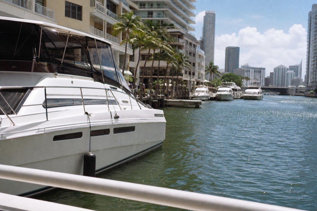 Yachts moored at a downtown Miami marina beside a waterfront shopping complex, no text, no logos, no people
